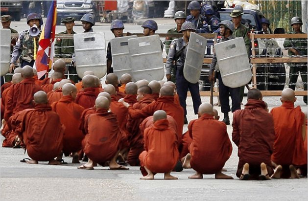 A group of monks sit in protest after being halted by riot officers and military officials in Myanmar (September 2007)